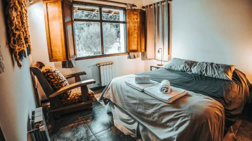 a bedroom with a bed and a chair and a window at Sombra Verde in Villa La Angostura