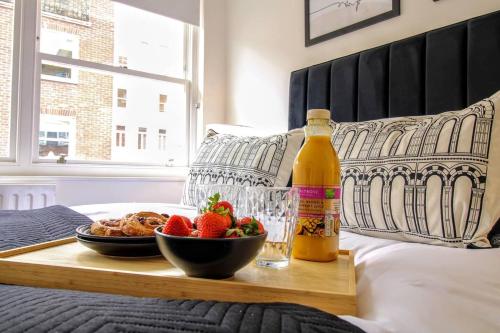 a bottle of wine and a bowl of fruit on a bed at London South Kensington mews house near Natural History Museum and tube in London