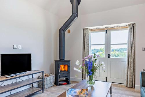 a living room with a wood stove in it at Dairy Barn by Bloom Stays in Groombridge