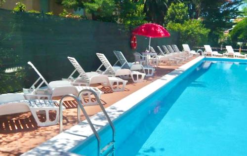a row of chairs and an umbrella next to a swimming pool at Residence with swimming-pool in Marina di Cecina just 700 meters from the beach in Cecina