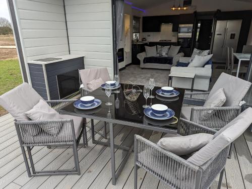 a patio with a table and chairs and a living room at Waterside Lodge - Stunning - Dog Friendly in Sutton on Sea