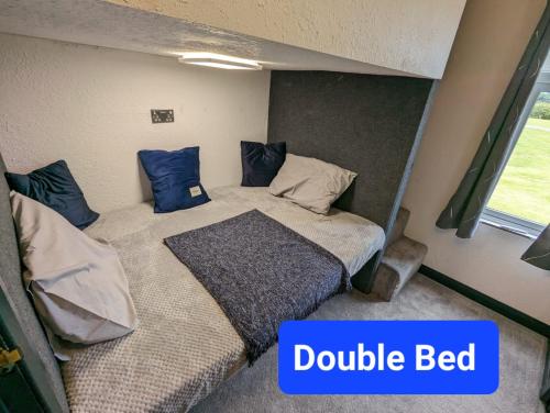 a bedroom with a double bed with blue pillows at Waterside Lodge - Stunning - Dog Friendly in Sutton on Sea