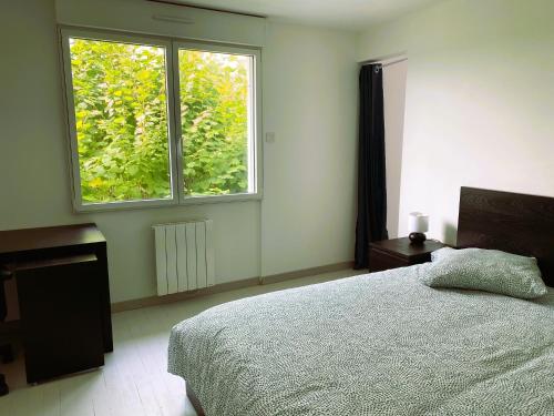 a bedroom with a bed and a large window at La troglo aux oiseaux in Montrichard