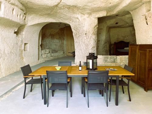 a wooden table and chairs in a stone room at La troglo aux oiseaux in Montrichard
