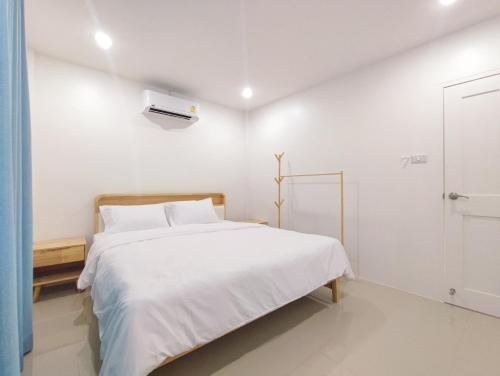 a white bedroom with a bed and a window at Sealife4 Beach Pool Villa in Rayong