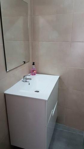 y baño con lavabo blanco y espejo. en Casa das Matriarcas- Casa da Avó Raquel, en Belmonte