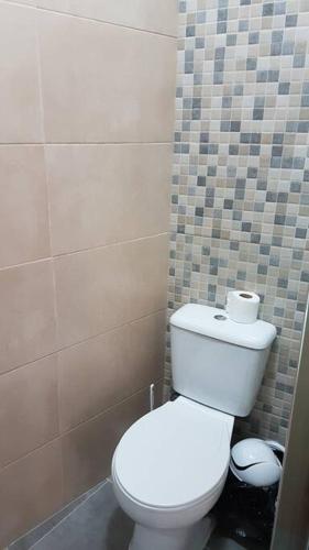 a bathroom with a white toilet and a tiled wall at Casa das Matriarcas- Casa da Avó Raquel in Belmonte