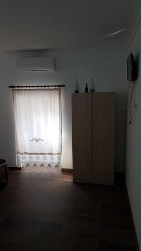 a room with a window and a dresser and a curtain at Casa das Matriarcas- Casa da Avó Raquel in Belmonte