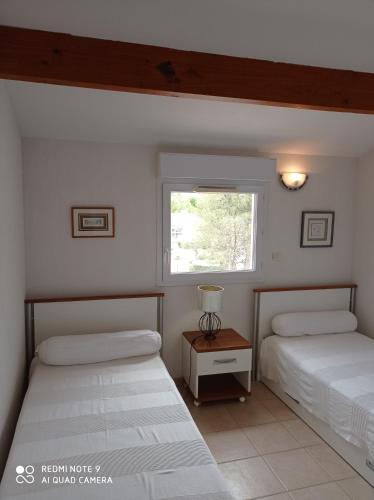 Duas camas num quarto com uma janela em Ombre et soleil vue sur la lagune et bateaux em Saint-Cyprien