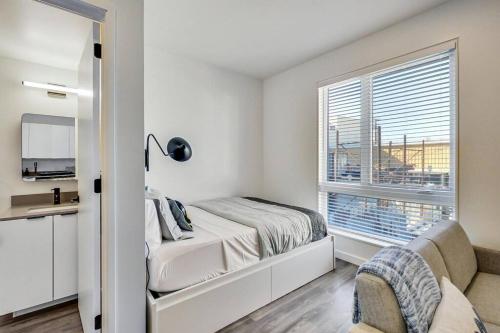 a white bedroom with a bed and a window at Stylish Studio in Laney-Peralta in Oakland