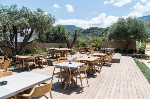 a patio with tables and chairs and trees at Alissachni SeaSide Hotel in Derveni