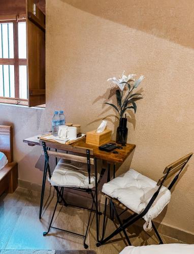 a desk with two chairs and a table with flowers at Alaqur View Inn نزل واجهة العقر in Nizwa