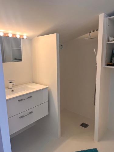 a white bathroom with a sink and a mirror at Belle chambre spacieuse, tropézienne, vue remparts, clim, parking in Aigues-Mortes