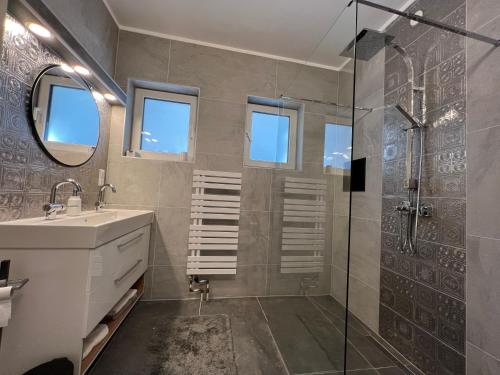 a bathroom with a shower and a sink and a mirror at Haus Bartberg in Pressbaum
