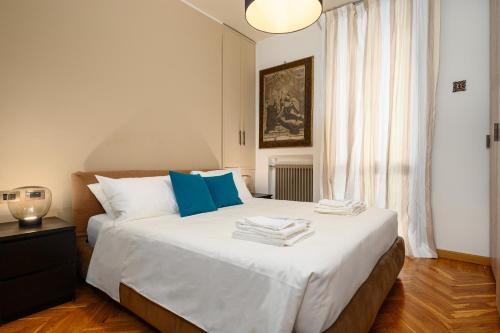 a bedroom with a large white bed with blue pillows at Happy Repubblica Milano in Milan