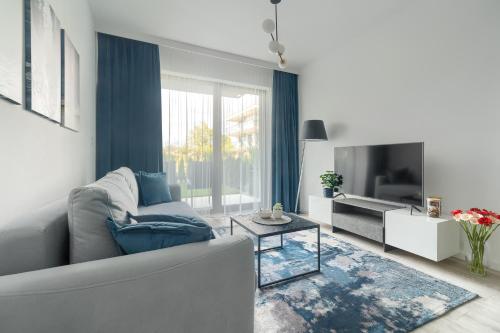 a living room with a couch and a tv at Nadmorski Apartament z ogródkiem przy plaży 114 Rezydencja Niechorze in Niechorze