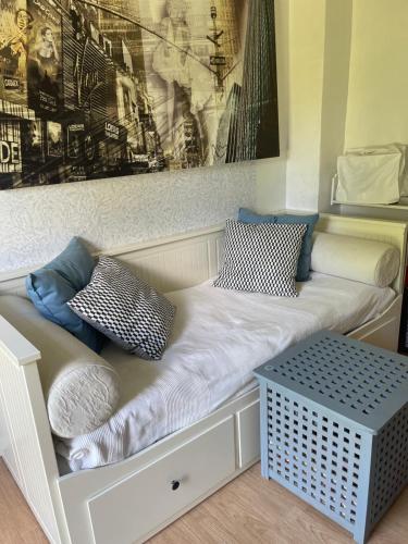 a white bench with pillows and a painting on a wall at The Old Henhouse in Tollarp