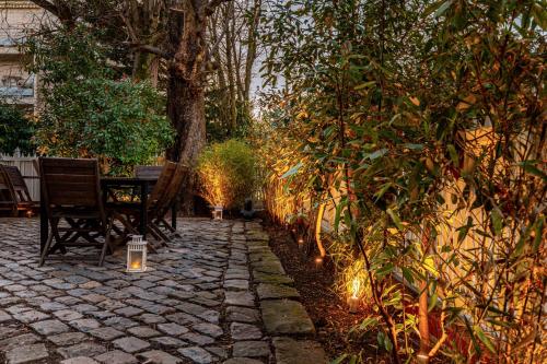 a patio with two chairs and a table and a tree at Art & Curiosity Cabinet Style Appartement with Paris view, Villa des Ammonites in Meudon
