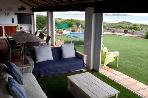 um pátio com um sofá azul, uma mesa e uma vista. em Bokmakierie Villa em St Helena Bay