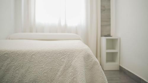 a bedroom with a white bed and a window at Hotel Restaurante Boabdil in Otura