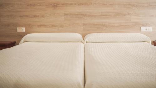 two white beds in a room with wooden floors at Hotel Restaurante Boabdil in Otura