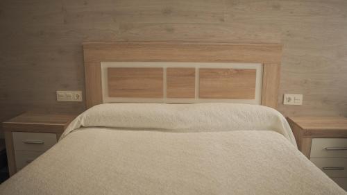 a bedroom with a bed with a wooden headboard at Hotel Restaurante Boabdil in Otura