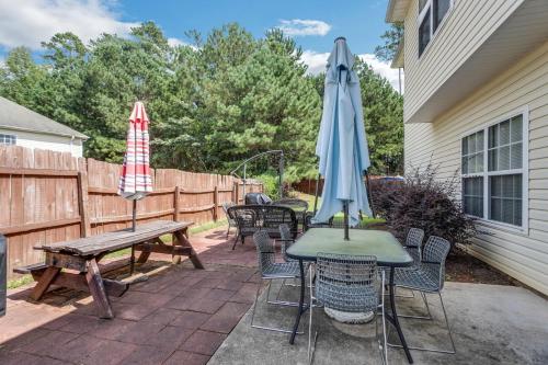 un patio con mesas, sillas y una sombrilla en Atlanta Retreat with 2-Car Garage, Fenced Yard home, en Locust Grove