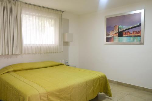 a bedroom with a yellow bed and a window at Hotel St. George in Celaya