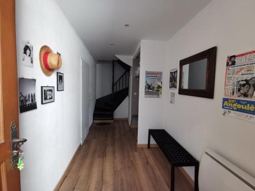 a hallway with white walls and wooden floors and a bench at Maison de ville le 101 - 3 chambres - garage in Angoulême
