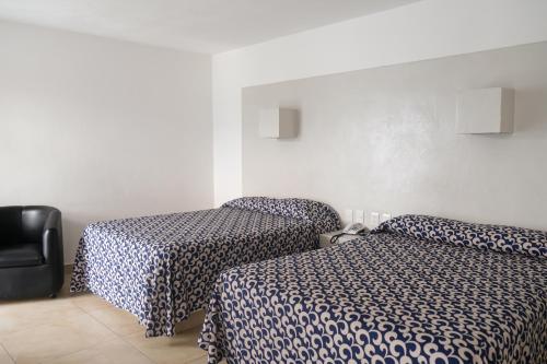a hotel room with two beds and a chair at Hotel St. George in Celaya