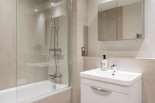 y baño blanco con lavabo y ducha. en Vauxhall Skyline Apartment, en Londres