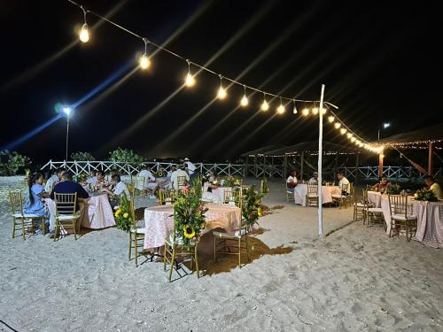 a group of people sitting at tables in a tent on the beach at Playa Escondida Mayapo in Mayapo