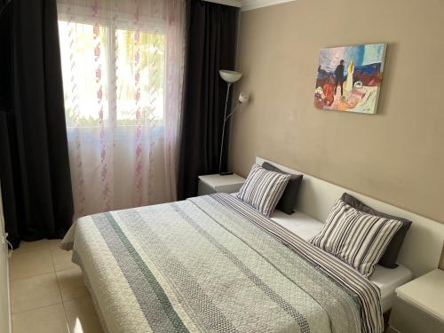 1 dormitorio con 1 cama con manta a rayas y ventana en Brisas del Mar, en Los Abrigos