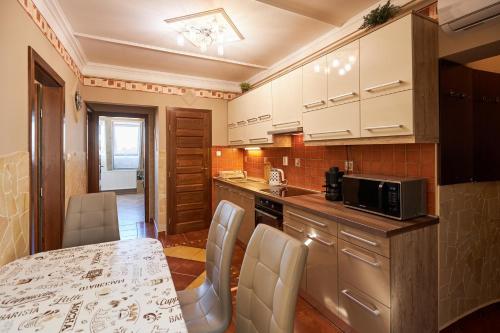 ハイドゥソボスローにあるValentin Deluxe Apartmanのキッチン(テーブル、椅子、電子レンジ付)