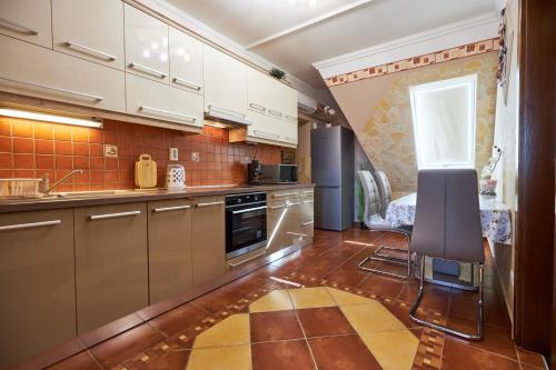 a kitchen with white cabinets and a table and chairs at Valentin Deluxe Apartman in Hajdúszoboszló