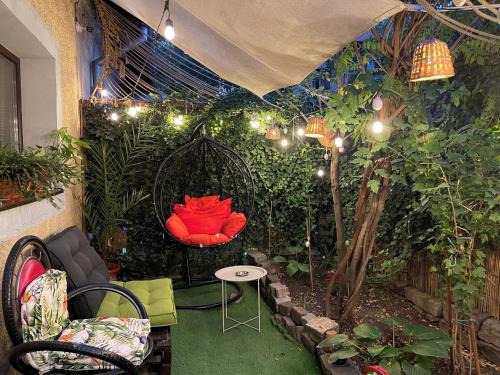 un jardin avec une chaise rouge dans une pièce ornée de plantes dans l'établissement City Garden Apartments, à Bucarest