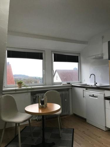eine Küche mit einem Tisch und Stühlen sowie 2 Fenstern in der Unterkunft Sonnenblick in Bad Nenndorf