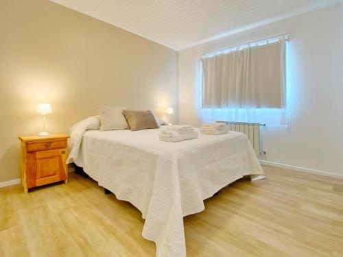 a white bedroom with a bed and a window at KAU KOSTEN in El Chalten