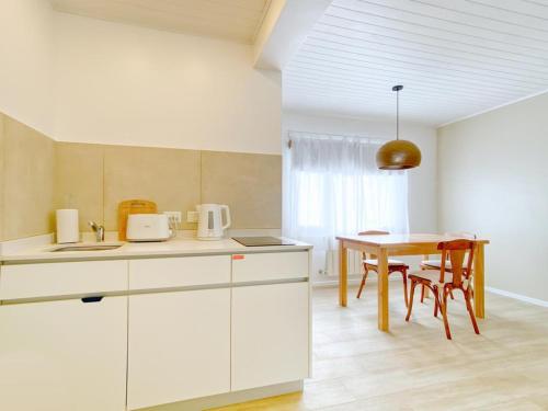 Una cocina con gabinetes blancos y una mesa con sillas. en KAU KOSTEN, en El Chaltén