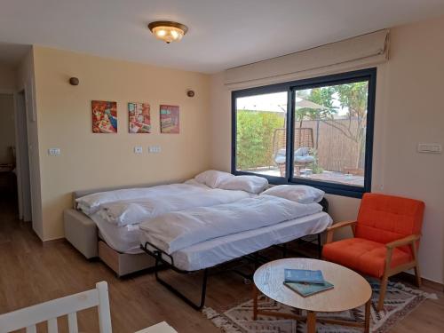 1 dormitorio con 1 cama, 1 silla y 1 ventana en אתיטיוד בערבה attitude at the arava en H̱aẕeva