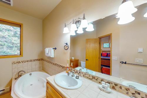 y baño con bañera, lavabo y espejo. en Cool Ridge Town Home at Summerwood en Keystone
