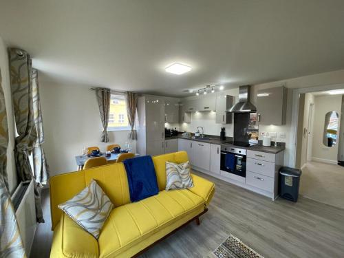 a living room with a yellow couch and a kitchen at Spacious Apartment in Brooklands in Milton Keynes