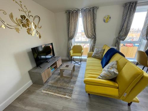 a living room with a yellow couch and a tv at Spacious Apartment in Brooklands in Milton Keynes