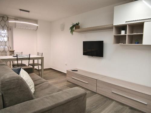 een woonkamer met een bank en een tv aan de muur bij THE BAC HOUSE - Maestrale in Fano