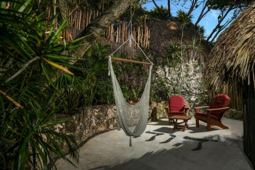 a hammock and two chairs in a garden at Diamante K - Inside Tulum National Park in Tulum