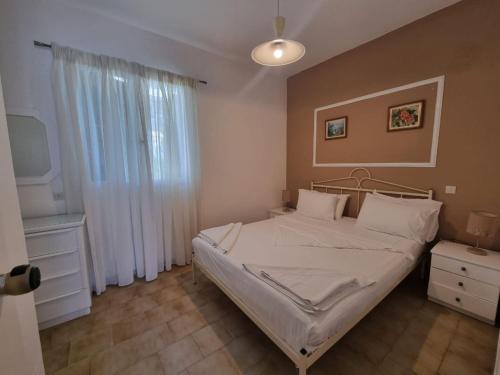 a bedroom with a white bed and a window at Corfu Dream Holidays Villas in Glyfada
