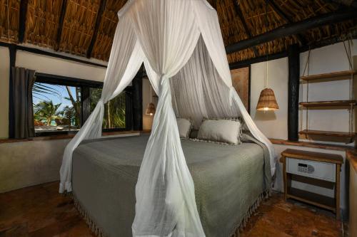 a bedroom with a bed with a mosquito net at Diamante K - Inside Tulum National Park in Tulum