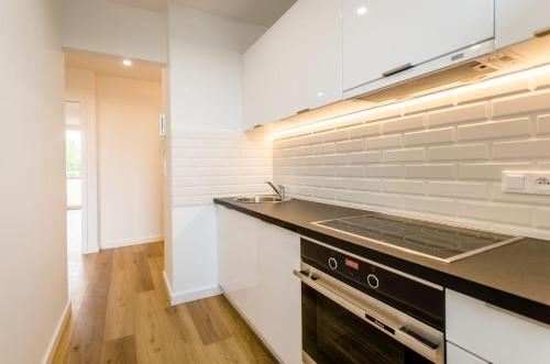 a kitchen with white cabinets and a stove top oven at Apartament Krasiczyńska in Warsaw