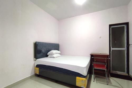 a small white room with a bed and a chair at OYO 93175 Wisma Syariah Dian in Barru