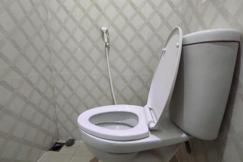 La salle de bains est pourvue de toilettes blanches avec un couvercle. dans l'établissement OYO 93175 Wisma Syariah Dian, à Barru